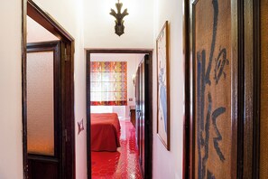A hallway with a red carpet leading to a room with a bed. - Luna Rossa, Capri (Capri)