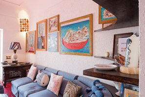 A living room with a blue sofa, decorative pillows, a wall with framed artworks, and a small table with a lamp and decorative items. - Luna Rossa, Capri (Capri)