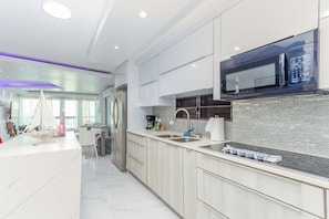A modern kitchen with a built-in microwave, stainless steel appliances, and a marble countertop. - Palomino & Icacos Trips / Near El Yunque & Bio Bay (Fajardo)