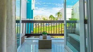 A balcony with a view of a cityscape, a potted plant, and a wicker bench. - Palomino & Icacos Trips / Near El Yunque & Bio Bay (Fajardo)
