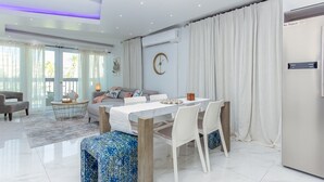 A modern living room with a dining area, a sofa, a coffee table, and a large window with curtains. - Palomino & Icacos Trips / Near El Yunque & Bio Bay (Fajardo)