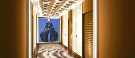 A hallway with patterned flooring, a framed artwork on the wall, and a patterned door.