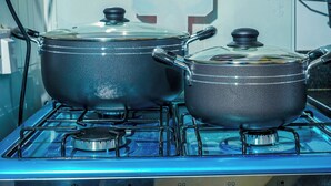 Deux casseroles sur une cuisinière à gaz, avec une prise de courant visible et un panneau de commande fixé au mur.