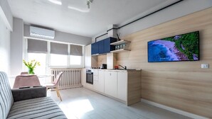 A modern kitchen with white cabinets, a built-in oven, and a large TV on the wall. - Modern&Cozy in Bacau *Wi‑Fi, AC, Smart TV,  Free Parking (Bacău)