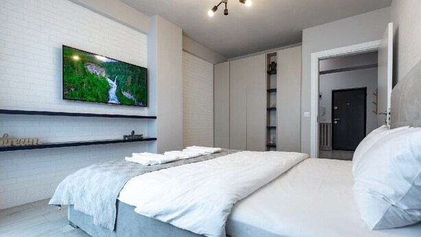 A modern bedroom with a bed, a flat-screen TV mounted on the wall, and a wardrobe. - Modern&Cozy in Bacau *Wi‑Fi, AC, Smart TV,  Free Parking (Bacău)