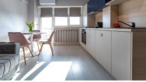 A modern kitchen with a dining area, a radiator, and a window with blinds. - Modern&Cozy in Bacau *Wi‑Fi, AC, Smart TV,  Free Parking (Bacău)