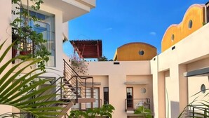 Un immeuble à plusieurs étages doté de balcons, d’escaliers et de plantes en pot.