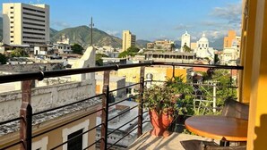 Un balcon donnant sur les bâtiments de la ville, avec une table et une chaise.