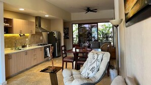 Une cuisine moderne avec des meubles en bois, un coin repas comprenant une table et des chaises, et un ventilateur de plafond.