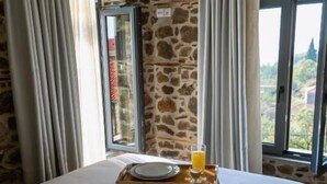 Uma cama com bandeja de café da manhã, cortinas e uma parede de pedra.