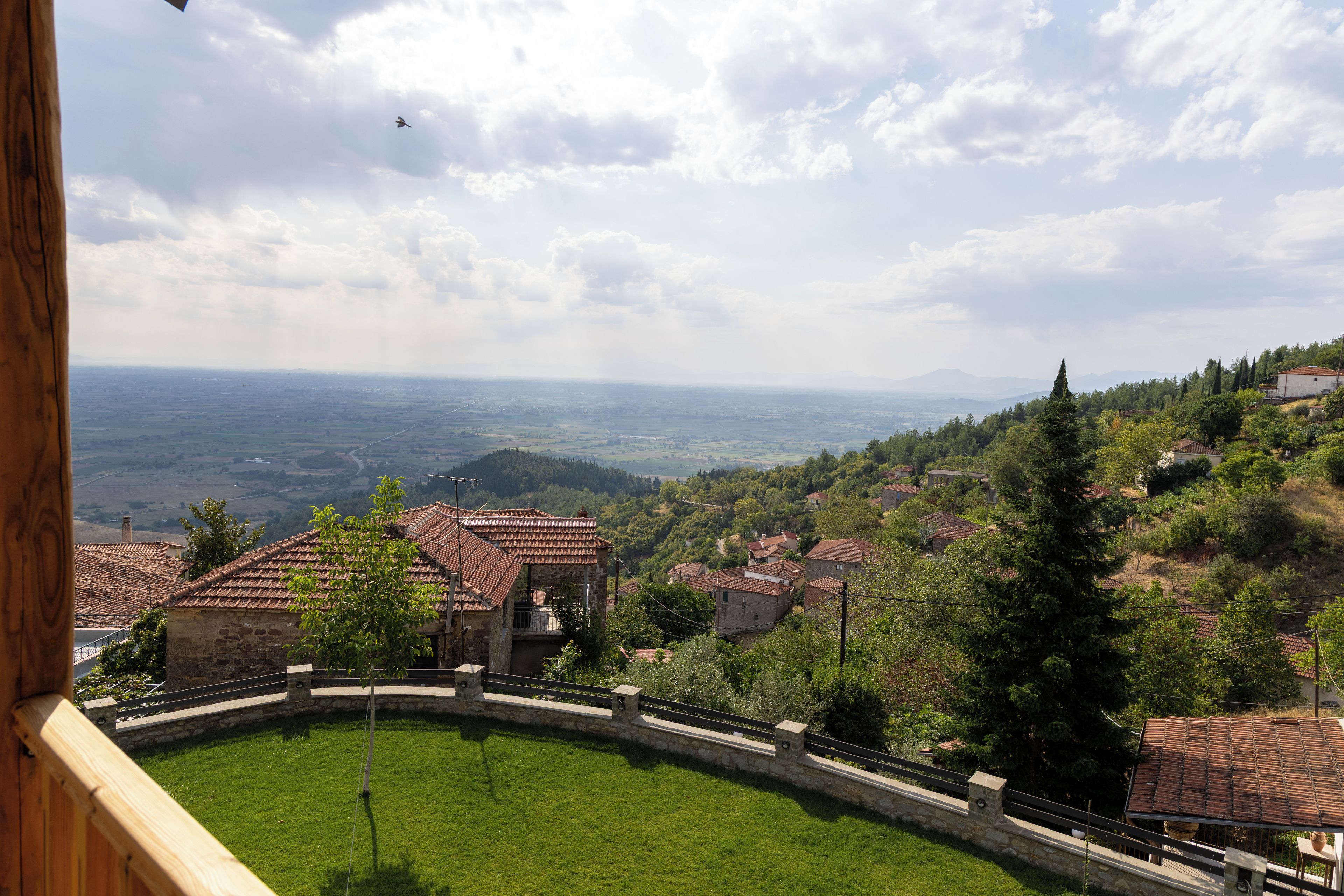 Vista de un paisaje rural con casas escalonadas, un área con césped y una lejana perspectiva del campo.