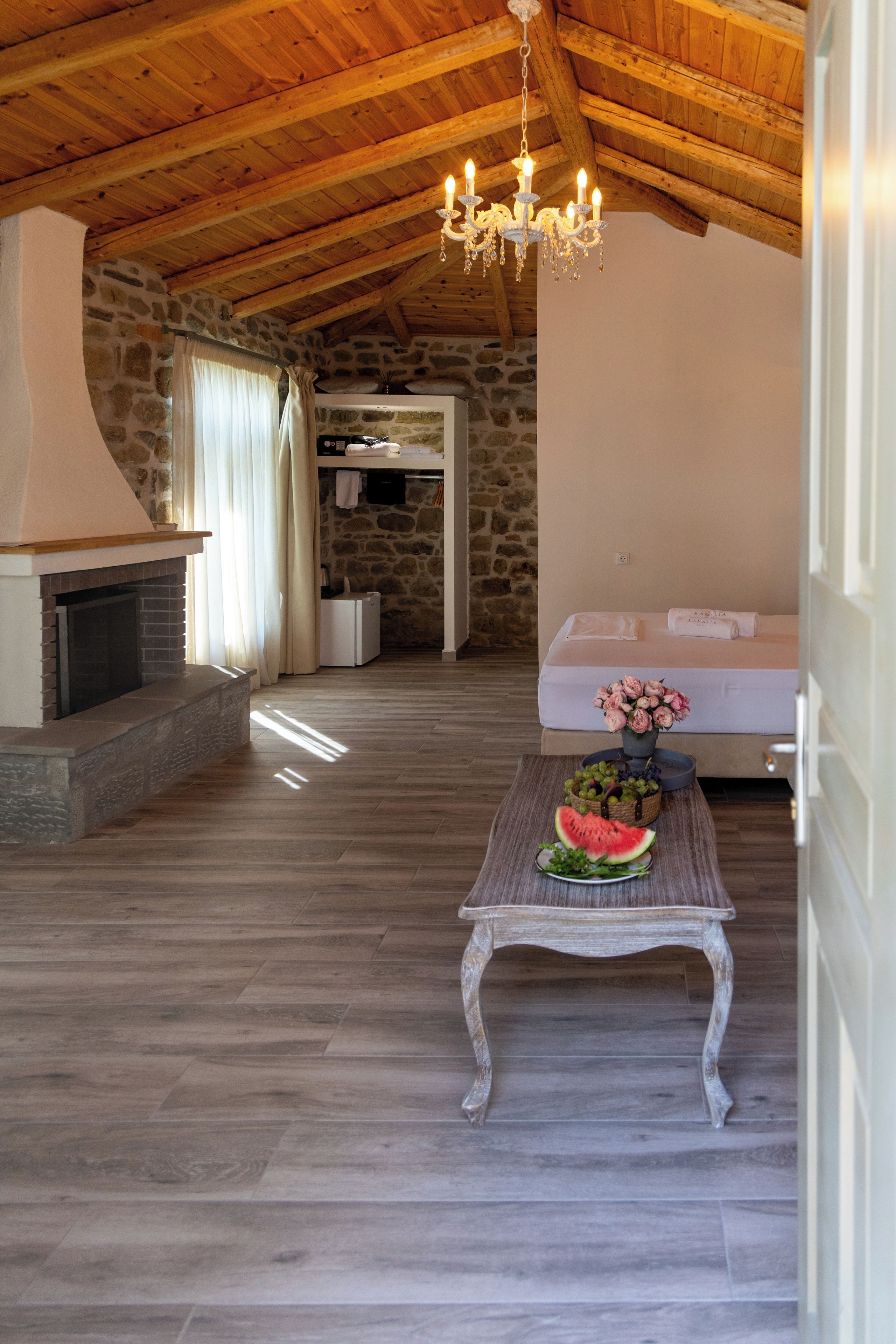 Un interior rústico con pared de piedra, techo de madera y chimenea.