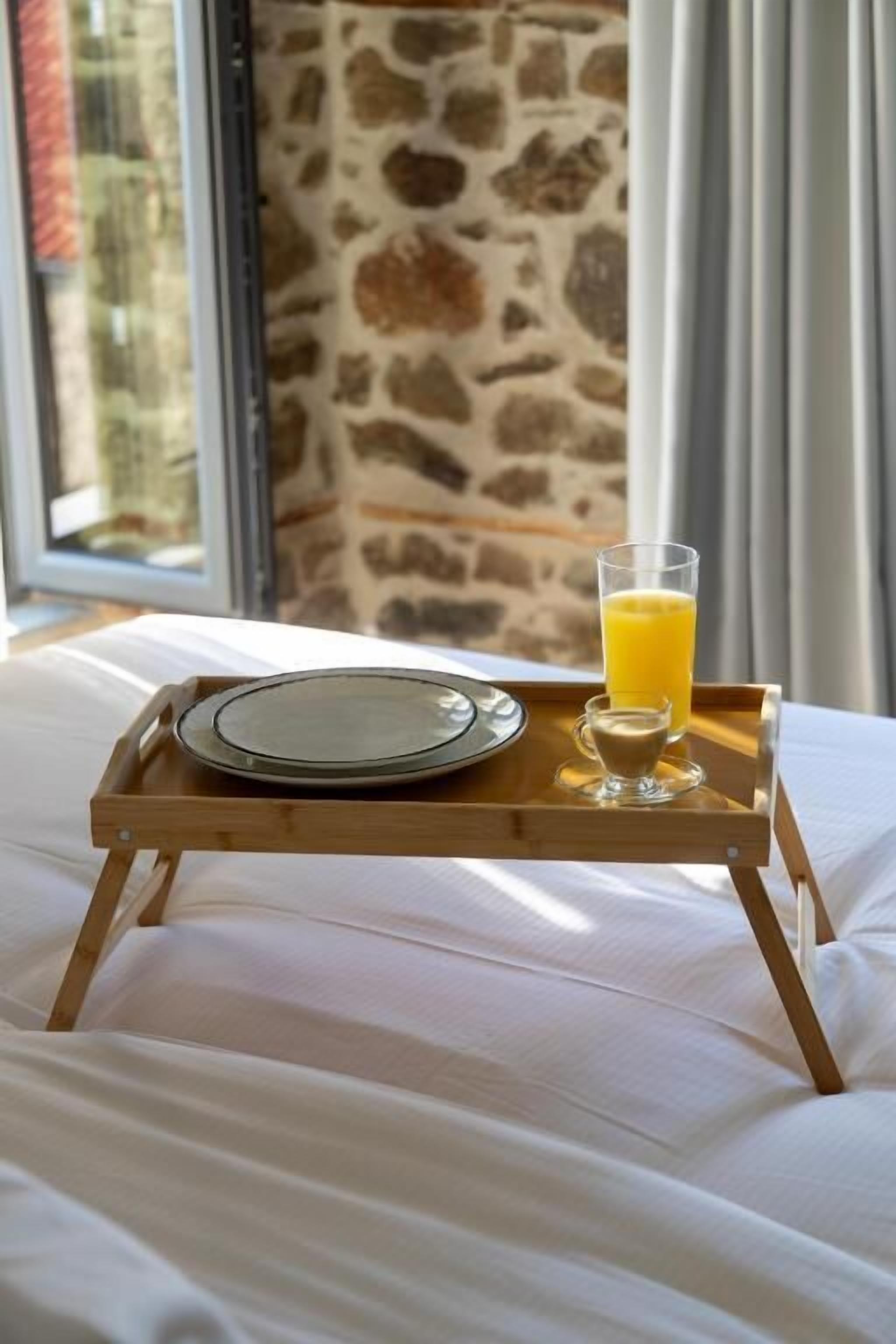 Una bandeja con un plato y un vaso de jugo de naranja sobre una cama con ropa blanca.