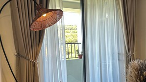 A room with a view to the outside, a wicker lamp, a cushioned chair, and a vase with dried plants. - 1991 Home Sapa | Fully Equipped Apartment | 5 min to Sapa Center (Sa Pa)