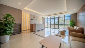 A modern hotel lobby with a reception desk, seating area, and large windows offering a view of the city. - 1991 Home Sapa | Fully Equipped Apartment | 5 min to Sapa Center (Sa Pa)