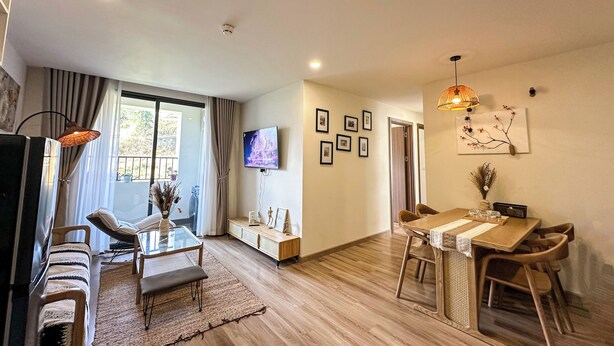 A modern living room with a sofa, TV, and dining area with chairs and a table. - 1991 Home Sapa | Fully Equipped Apartment | 5 min to Sapa Center (Sa Pa)