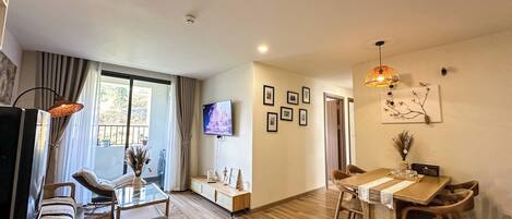 Un salon moderne comprenant un canapé, un téléviseur et un coin repas avec des chaises et une table.