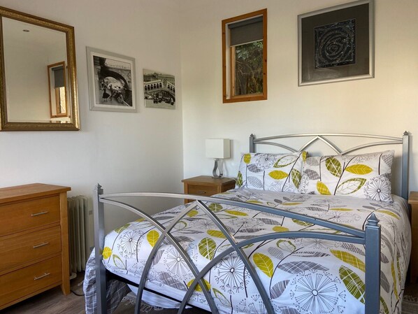 Une chambre à coucher avec un lit en métal, une commode en bois et un radiateur.