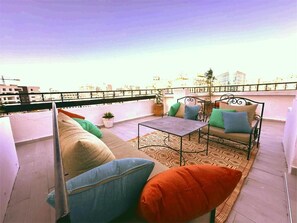 A rooftop terrace with a sofa, a small table, and a metal chair. - In the center of Tangier, vintage penthouse with 4 bedrooms and stunning terrace (Tanger)