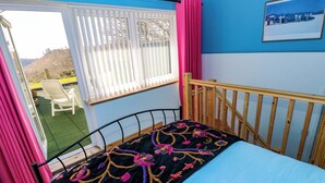 Een kamer met een bed, een raam met jaloezieën, een stoel en een schilderij aan de muur.