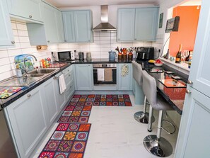 A compact kitchen with light blue cabinets, a microwave, a kettle, and a coffee maker. - 51 Llanteg Park (Narberth)