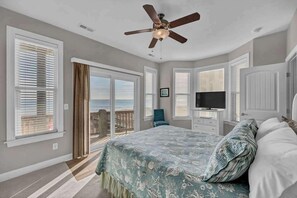 A bedroom with a large bed, a ceiling fan, a TV, and a sliding glass door to a balcony. - Aqua Sea, a beachfront retreat (Carolina Beach)