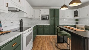 A modern kitchen with white cabinets, a microwave, a stove, and a bar area. - Stay@Black Sheep:Lakefront•HotTub•No Steps2Dock! Spacious_Location_Dog friendly (New Tazewell)