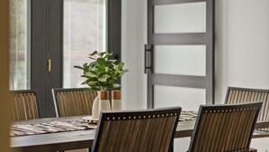 A dining area with a table set for six, wooden chairs, and a potted plant on the table. - Stay@Black Sheep:Lakefront•HotTub•No Steps2Dock! Spacious_Location_Dog friendly (New Tazewell)