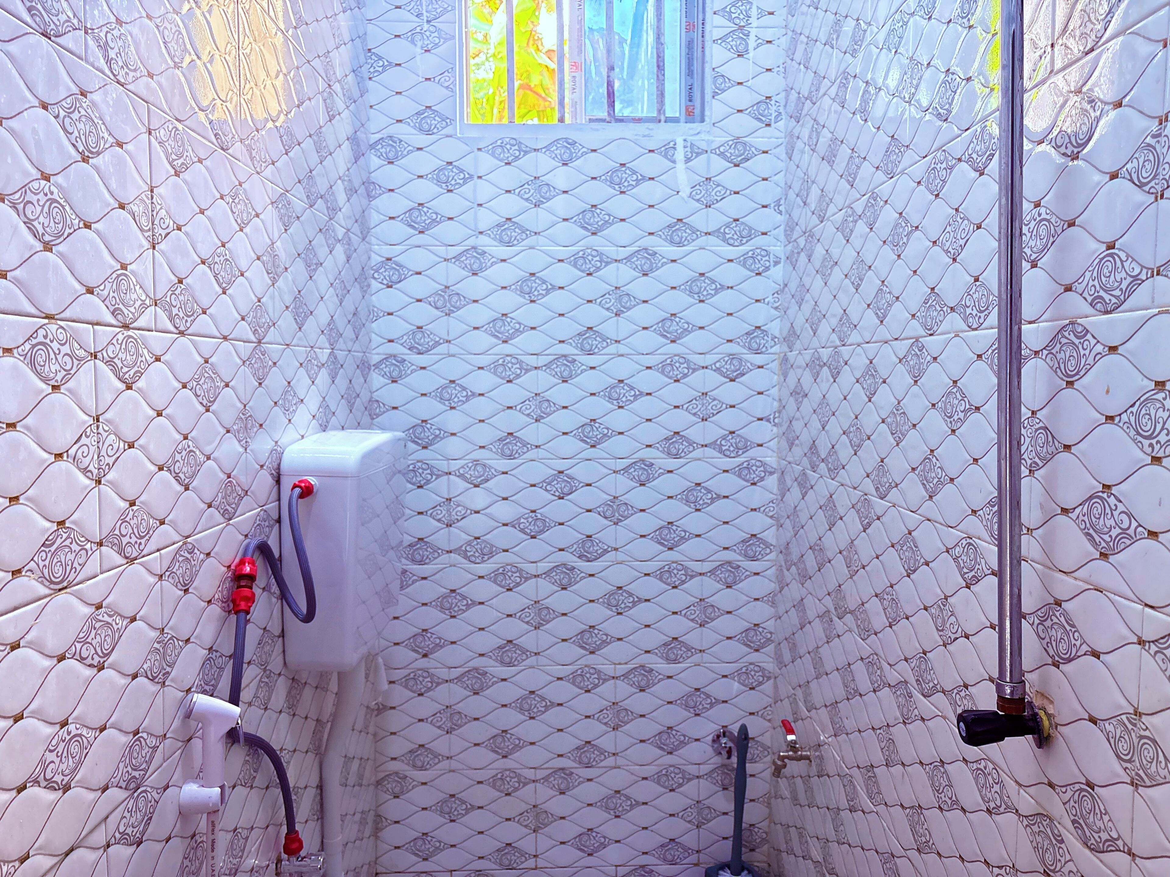 Une salle de bain avec des carreaux décorés, une fenêtre et un espace douche.