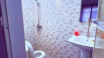A bathroom with a shower, toilet, and sink.