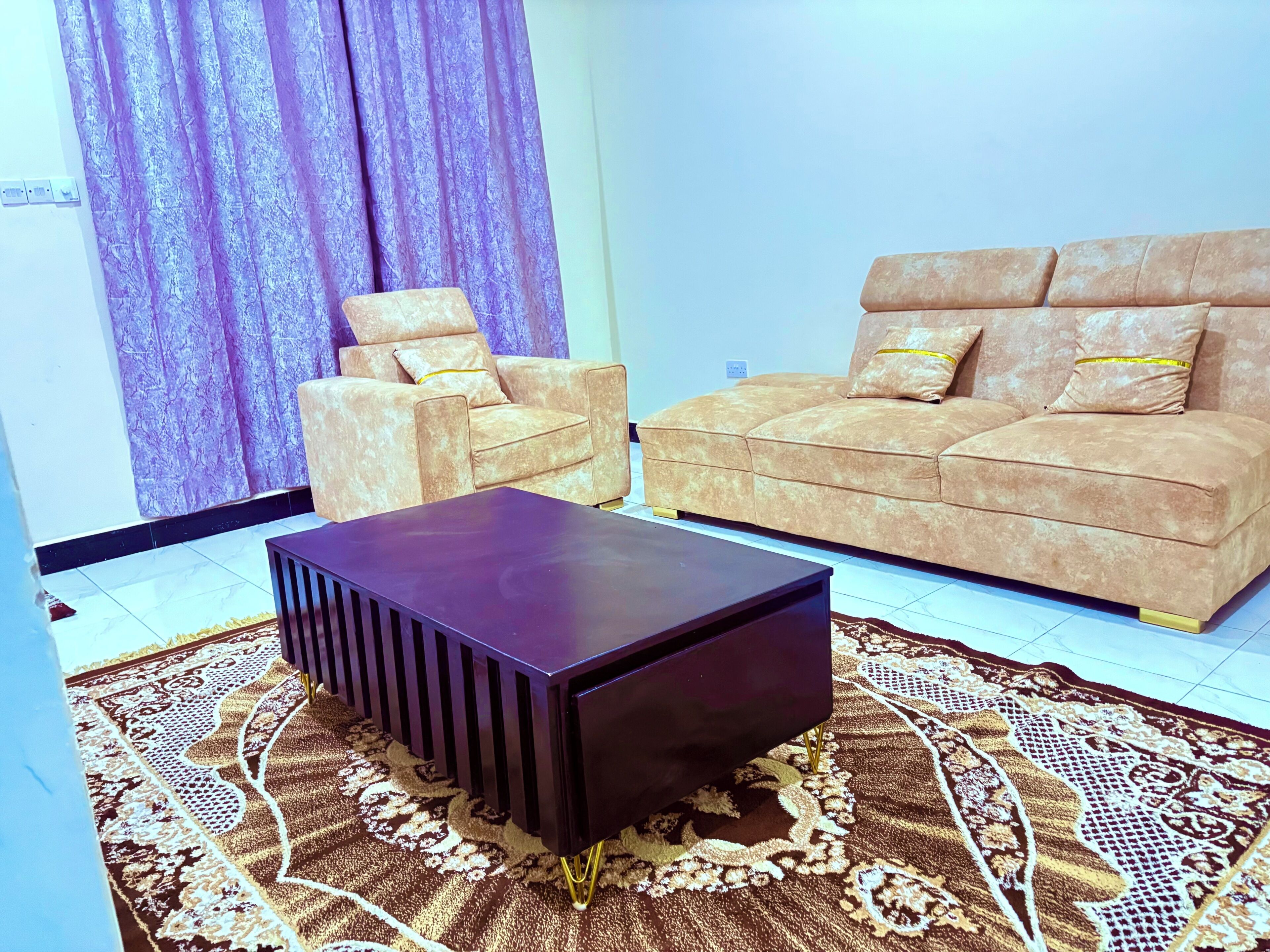 Ein Wohnzimmer mit Sofa, Sessel und einem dunkelbraunen Couchtisch.