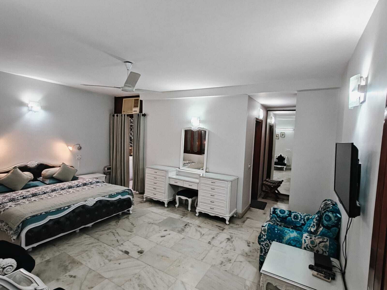 Un dormitorio con cama, cómoda, espejo y televisor.