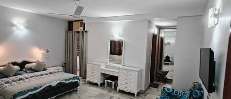 Un dormitorio con cama, cómoda, espejo y televisor.