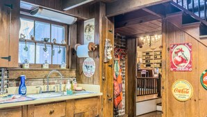 A rustic kitchen with wooden cabinets, a sink, and a window with house decorations. - Almeneiro Cabin - A Charming Nature Retreat (Greensboro)
