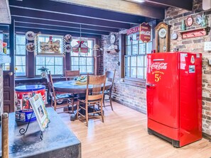 A kitchen with a wooden table, chairs, a red refrigerator, and vintage Coca-Cola memorabilia.