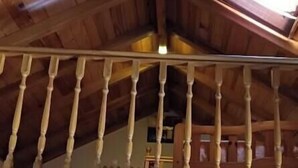 A wooden interior with a staircase, wooden beams, and a ceiling with a light fixture.