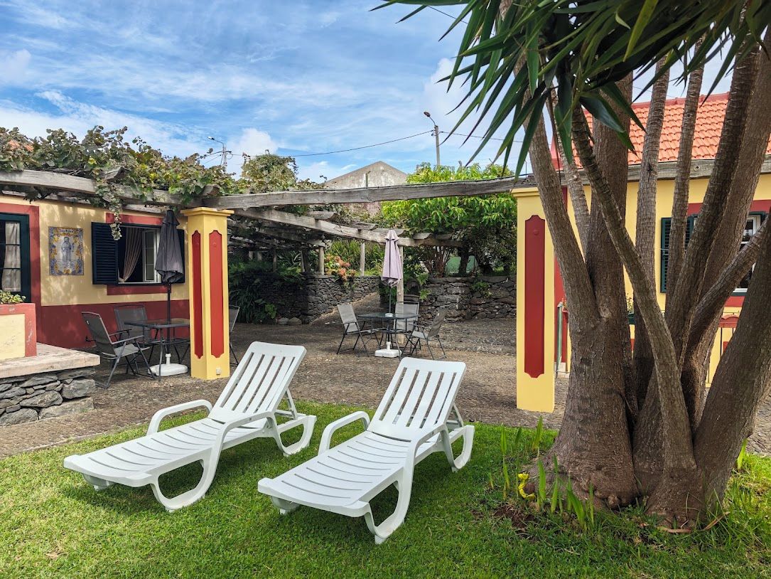 A patio area with two white lounge chairs, a table, and a pergola structure.