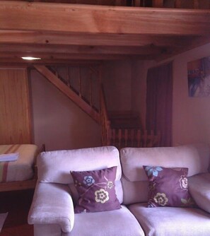 A wooden staircase, a sofa with floral cushions, and a bed with a striped blanket. - Herdade do Pedregal (Calheta)