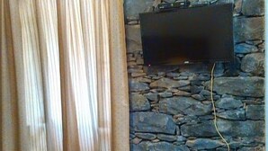 A room with a stone wall, a flat-screen TV mounted on it, and a curtain.