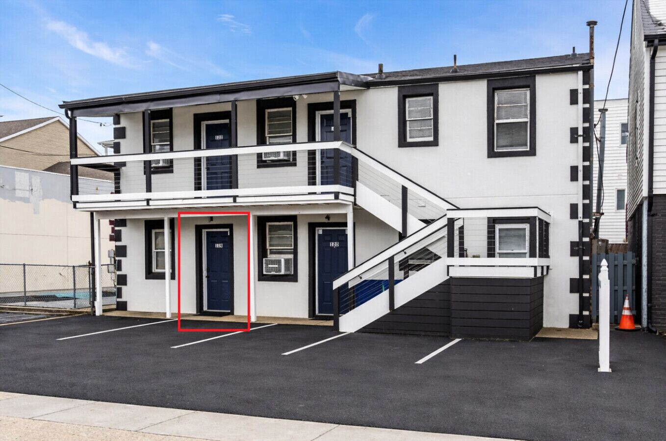 A two-story building with a flat roof, a front entrance, and a staircase leading to the upper floor.