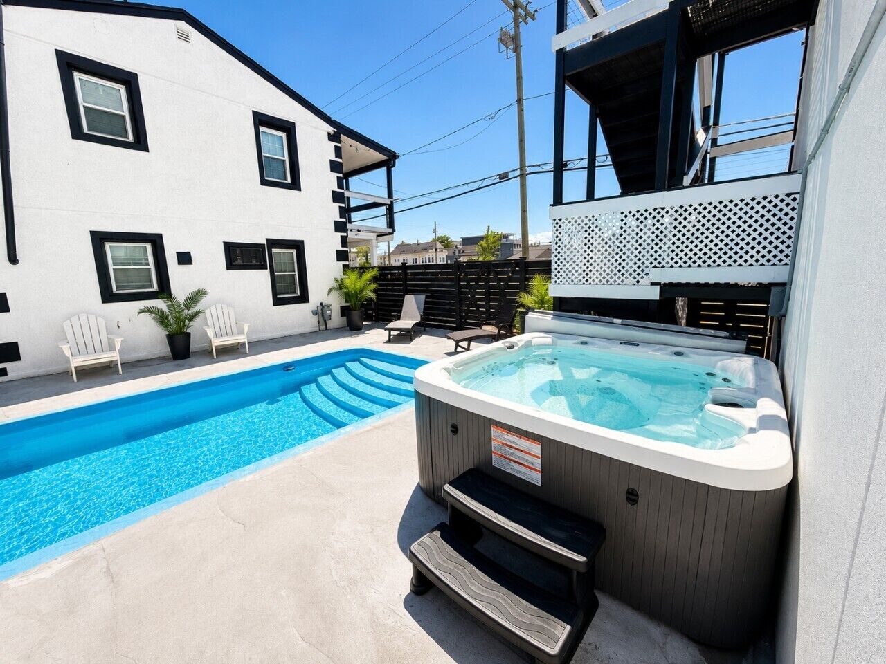 Piscina, jacuzzi y zona de estar al aire libre con un edificio al fondo.