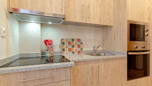 Una cocina con gabinetes de madera, campana extractora de acero inoxidable, horno doble y encimera de granito.