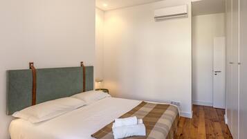 A neatly made bed with a headboard, a bedside lamp, and a folded towel on the bed.