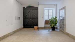 Ein Flur mit einer großen schwarzen Tür, einem Topfpflanzen und einem Fenster mit Jalousien.