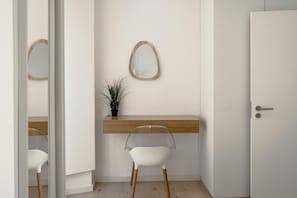 A minimalist room with a white door, a wooden desk with a plant, and a white chair. - Downtown Modern Apartments I by Homing (Lisbon)