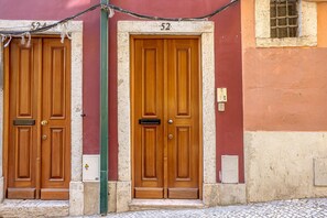 Two wooden doors with the number 52 above them, set in a building with a stone base and a tiled ground. - Downtown Modern Apartments I by Homing (Lisbon)