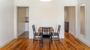 A dining area with a wooden table and chairs, white walls, and a wooden floor. - Bairro Alto Typical by Homing (Lisbon)