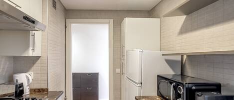 A compact kitchen with a gas stove, microwave, toaster, and a refrigerator.