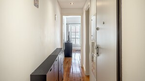 A narrow hallway with wooden flooring, a black bench, and a door on the right. - Bairro Alto Typical by Homing (Lisbon)
