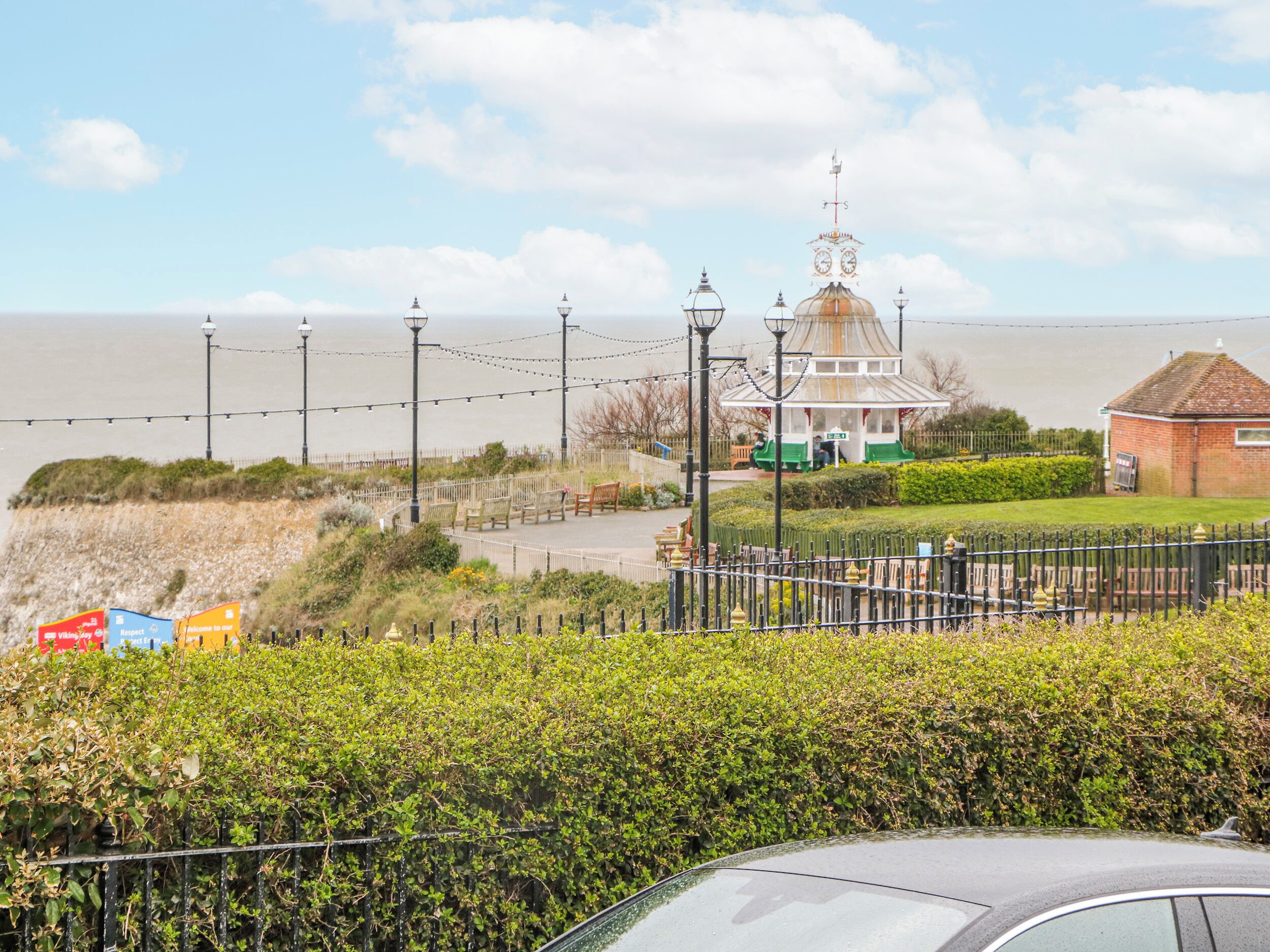 A coastal view with a gazebo, benches, and a fence.